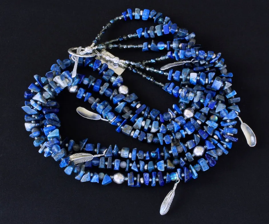 Lapis Lazuli Nugget 3-Strand Necklace with Bench-Made Sterling Silver Rounds, Sterling Silver Feather Charms, Translucent Blue Crystal Rounds, Labradorite Faceted Rounds, Fire Polished Glass, and Hammered Sterling Silver Toggle Clasp